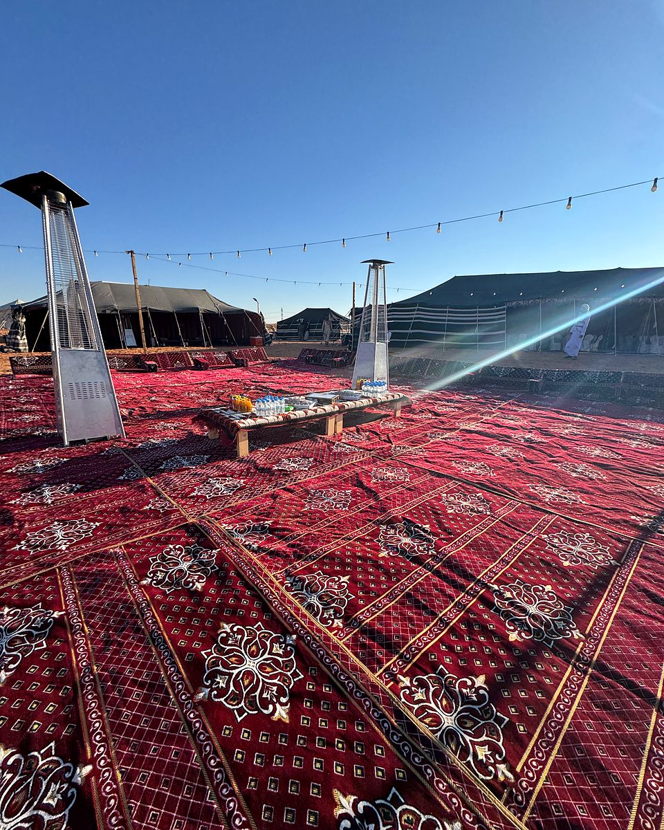 Traditional Saudi majlis seating with patio heaters at the desert camp in late-afternoon sun